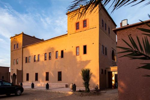 a large building with people standing outside of it at Kanz Erremal in Merzouga