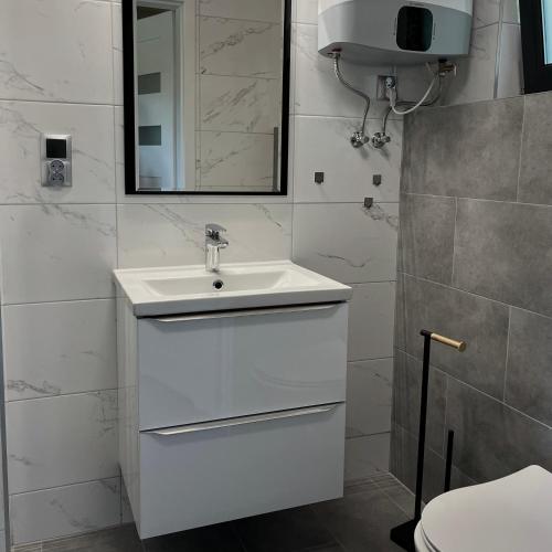 a white bathroom with a sink and a mirror at Stumilowy Las - Białe Domki in Mielenko