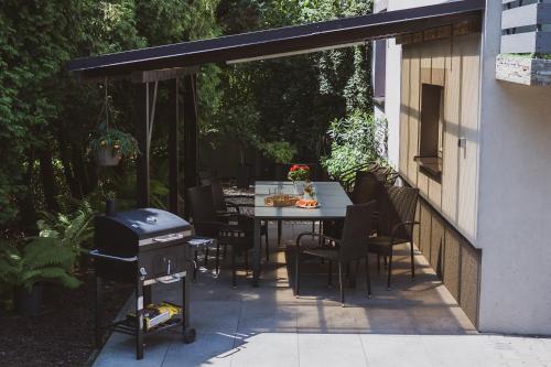 Un patio con mesa y sillas y parrilla. en Dom Marika - Energylandia Zator, en Zator