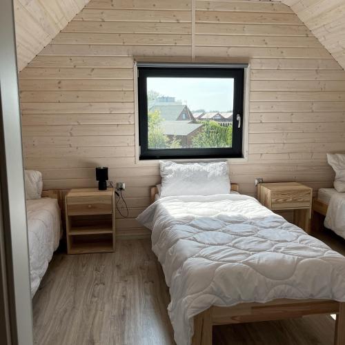 a small bedroom with two beds and a window at Stumilowy Las - Białe Domki in Mielenko