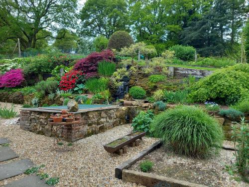 un giardino con una panchina in pietra e piante di Honey House a Midhurst