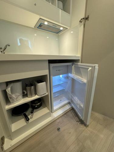 an empty refrigerator with its door open in a kitchen at Victoria Studios in London