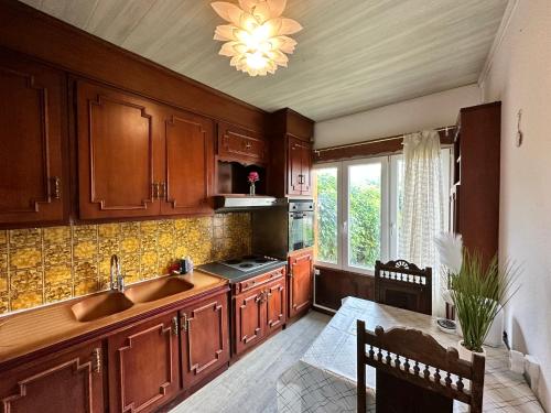 une cuisine avec des armoires en bois, un évier et une table dans l'établissement Appt Cosy - Proche Paris - Ideal Couple, à Fresnes