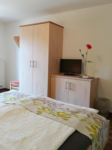 a bedroom with a bed with a tv and a cabinet at Landgasthof zum Rappen in Creglingen