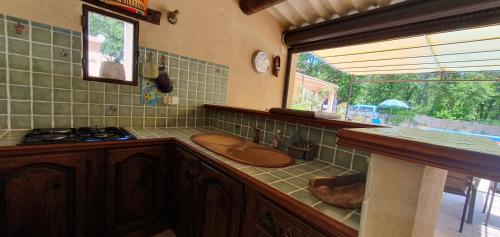 - une cuisine avec un évier et un comptoir avec une fenêtre dans l'établissement Maison familiale avec piscine et boulodrome dans le Luberon, à Caseneuve