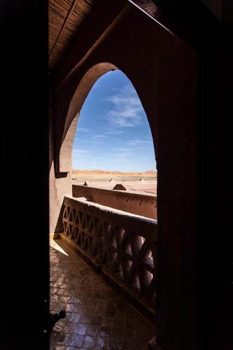 an archway in a building with a view of the desert at Kanz Erremal in Merzouga