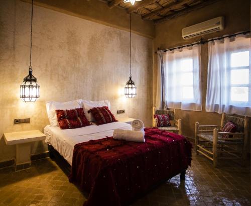 a bedroom with a bed and two pendant lights at Kanz Erremal in Merzouga