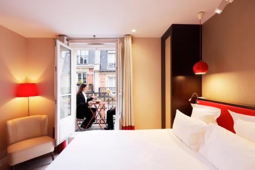 a hotel room with a bed and a woman sitting at Hotel Eden in Paris