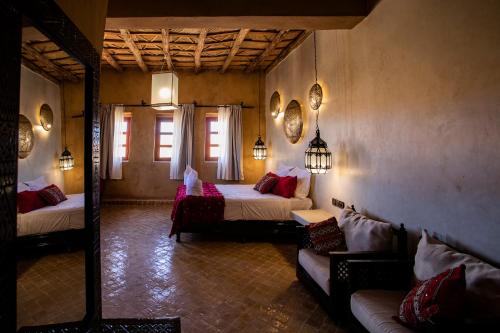 a room with two beds and a couch in it at Kanz Erremal in Merzouga