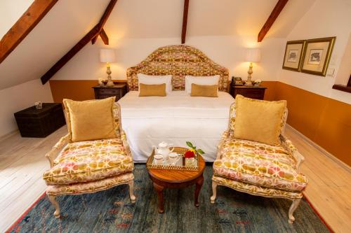a bedroom with a large bed and two chairs at Hotel du Vin Franschhoek in Franschhoek