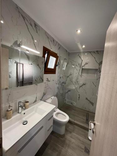 a bathroom with a white sink and a toilet at Victoria's Apartments in Nea Plagia