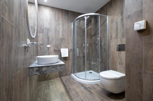 a bathroom with a shower and a toilet and a sink at Hotel Jarzębata in Wisła