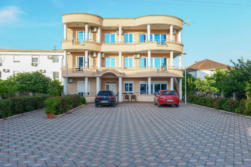a large building with two cars parked in a parking lot at Rexha Apartments in Ulcinj