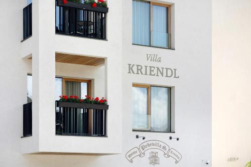 a facade of a white building with windows and red flowers at Kriendl Nr 3 in Valdaora
