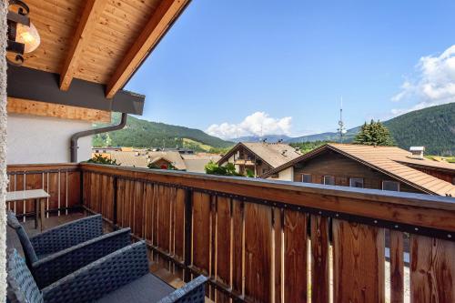 a balcony with two chairs and a table and mountains at Kriendl Nr 3 in Valdaora