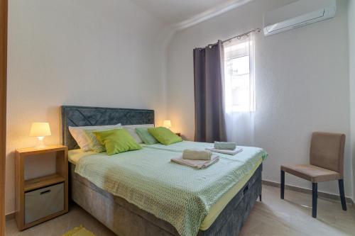 a bedroom with a bed with green pillows and a chair at Vila DADA 2 in Senj