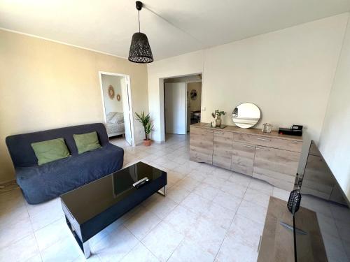 un salon avec un canapé bleu et un miroir dans l'établissement Charmant T2 de 42m2 calme tout équipé Parking gratuit, à Nîmes