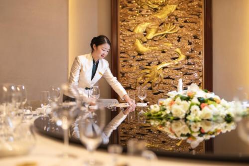 a woman standing in front of a table with wine glasses at voco Wuhan Xinhua by IHG in Wuhan