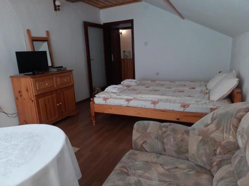 a bedroom with a bed and a couch and a television at Къща за гости Сара in Velingrad