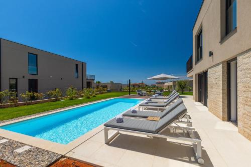 a row of lounge chairs next to a swimming pool at Beautiful Villa Vegt with pool in Labinci in Labinci