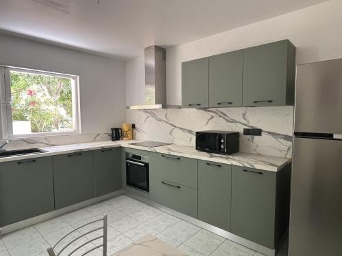 a kitchen with green cabinets and a window at Les Villas Maristella, Villa Goria in Aregno