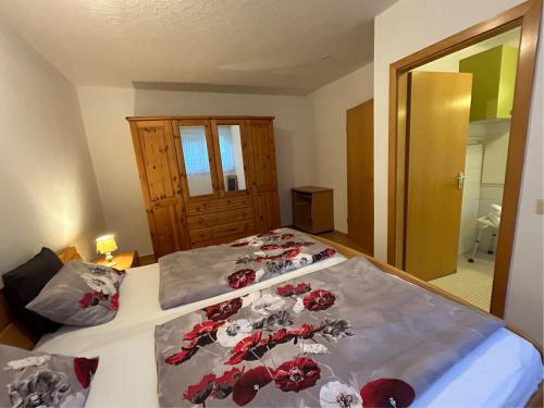a bedroom with a bed with red flowers on it at Haus Wegener in Bad Sassendorf