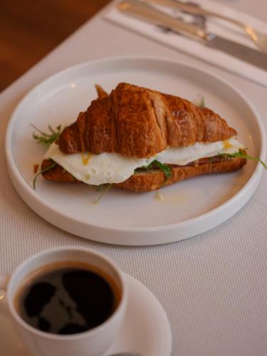 a sandwich on a plate next to a cup of coffee at Hotel Monopol in Wrocław