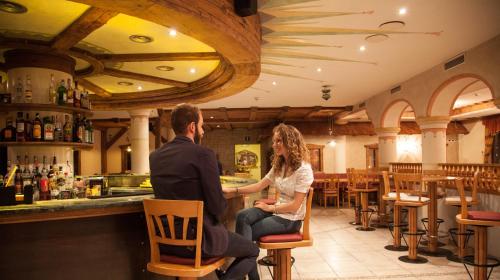 a man and a woman sitting in a bar at Hotel Comfort Erica Dolomiti Val d'Adige in Salorno sulla Strada del Vino