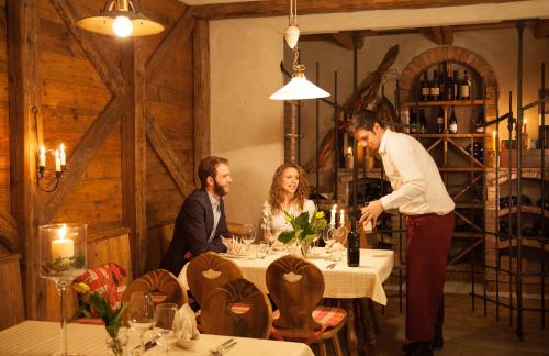 three people sitting around a table in a restaurant at Hotel Comfort Erica Dolomiti Val d'Adige in Salorno sulla Strada del Vino