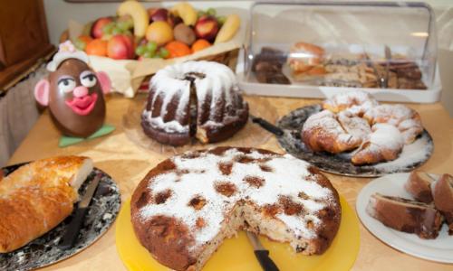 a table with different types of cakes and pastries at Hotel Comfort Erica Dolomiti Val d'Adige in Salorno sulla Strada del Vino