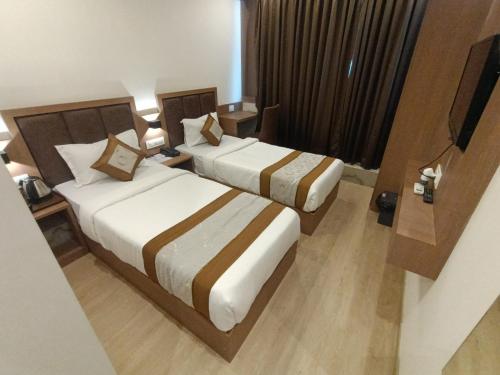 a hotel room with two beds and a television at Hotel Beverly Palace Santacruz - Near BKC - Mumbai Airport T1 in Mumbai