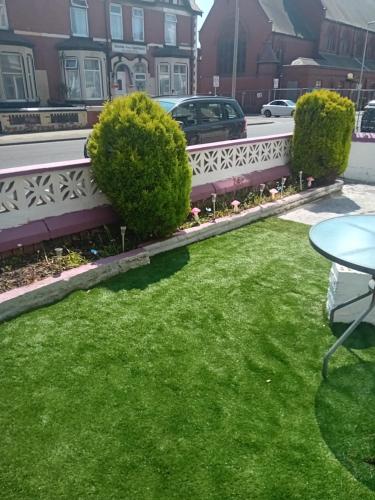 a yard with green grass and a bench at MyRoomz Orchid Hotel in Blackpool