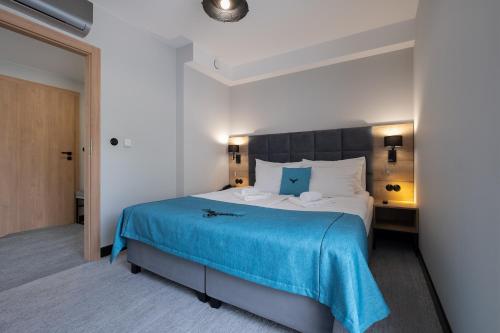 a bedroom with a large bed with a blue blanket at Hotel Jarzębata in Wisła