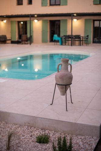un vase assis à côté d'une piscine dans l'établissement O Cabanon - Superbe Villa rénovée avec piscine privée, à Laroque-des-Albères