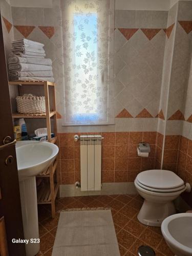 a bathroom with a toilet and a sink and a window at Mary House in Ladispoli