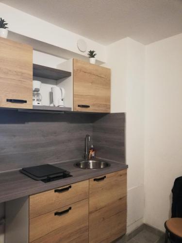 une cuisine avec un évier et des armoires en bois dans l'établissement JUNO, à Courseulles-sur-Mer