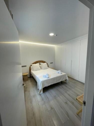 a bedroom with a white bed and a wooden floor at Selecta Marbella Sentire Apartaments in Marbella