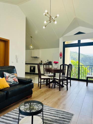 a living room with a black couch and a table at BoaVista- 2 bed house -COSY PANORAMIC -SEA - MOUNTAIN VIEW in Campanário