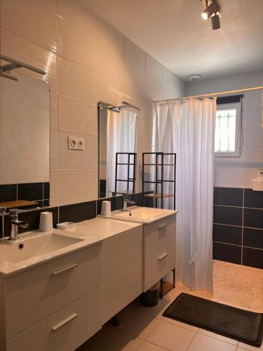 a bathroom with two sinks and a large mirror at La maison Opale, 10 mn du Zoo de Beauval in Saint-Romain-sur-Cher