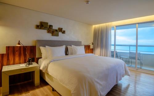 a bedroom with a bed with a view of the ocean at Hotel Luzeiros Fortaleza in Fortaleza