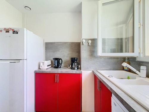 une cuisine avec des armoires rouges et un réfrigérateur blanc dans l'établissement Appartement en bord de plage avec terrasse, parking privé, wifi et équipements modernes - FR-1-770-15, à Saint-Cyr-sur-Mer