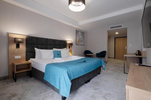 a bedroom with a large bed with a blue blanket at Hotel Jarzębata in Wisła