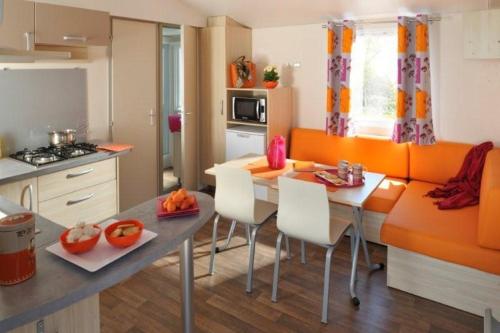 a kitchen with a table and chairs in a room at Camping Arquebuse in Auxonne