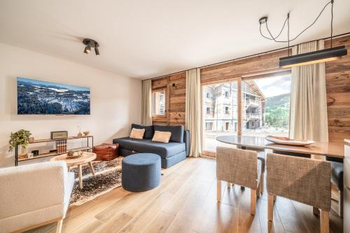 un salon avec un canapé bleu et une table dans l'établissement Apartment Aldea Les Gets - by EMERALD STAY, aux Gets