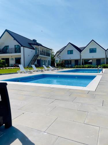 una piscina con sedie a sdraio di fronte a una casa di Białe Domki Paula SPA Niechorze a Niechorze