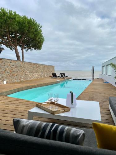 - une piscine avec une table et des chaises à côté de la plage dans l'établissement Villa Angoulins front de mer, à Angoulins-sur-Mer