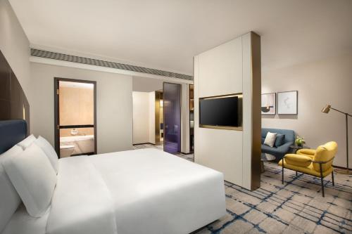 a hotel room with a large bed and a tv at voco Wuhan Xinhua by IHG in Wuhan
