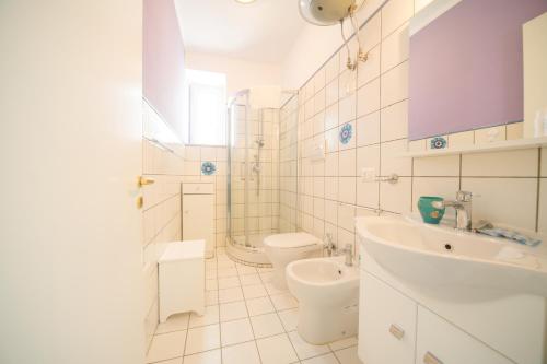 a white bathroom with a toilet and a sink at Le terrazze sulla spiaggia in Ascea