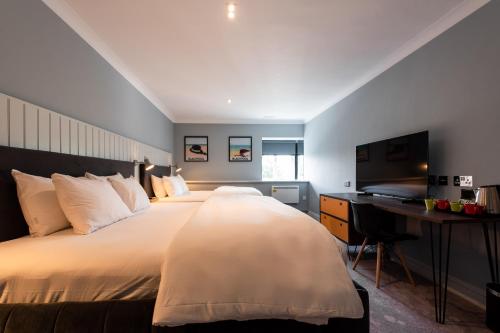 a bedroom with a large bed with a desk and a television at Village Hotel Blackpool in Blackpool