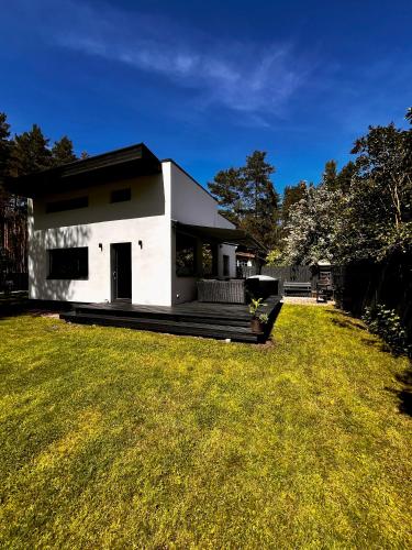 a white house with a large grass yard at Villa Gauja - holiday home close to the sea and lake in Gauja